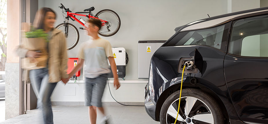 Mother and son charging EV in garage